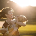 Mulher no campo com cachorro no colo